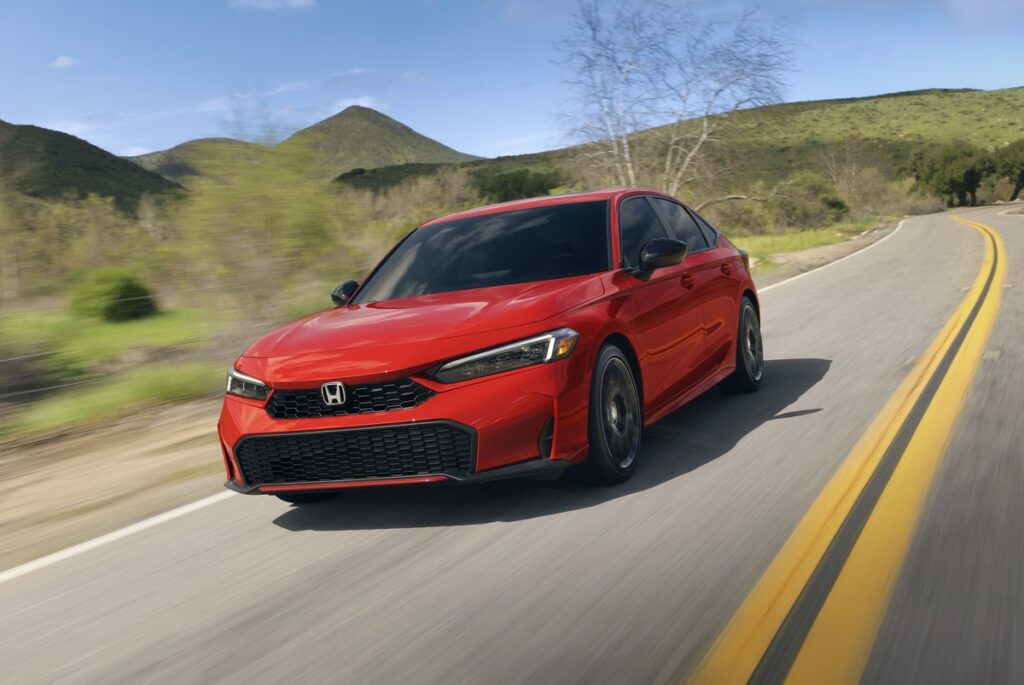 2026 Honda Civic Sedan in red driving on a scenic highway
