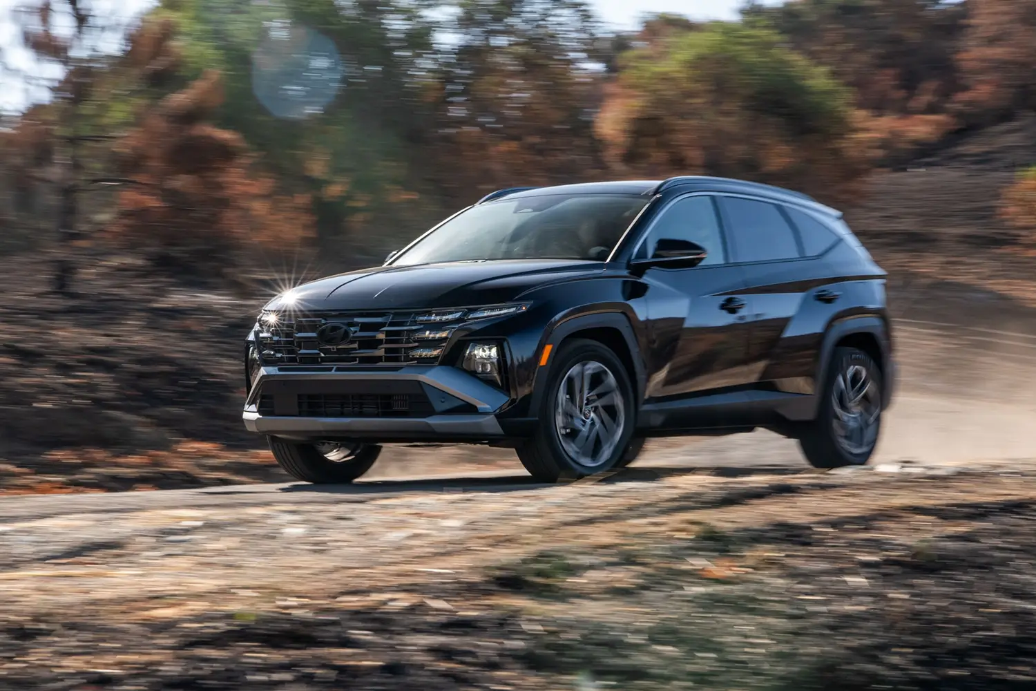 2026 Hyundai Tucson driving on a dirt road, showcasing its bold design and compact SUV stance.