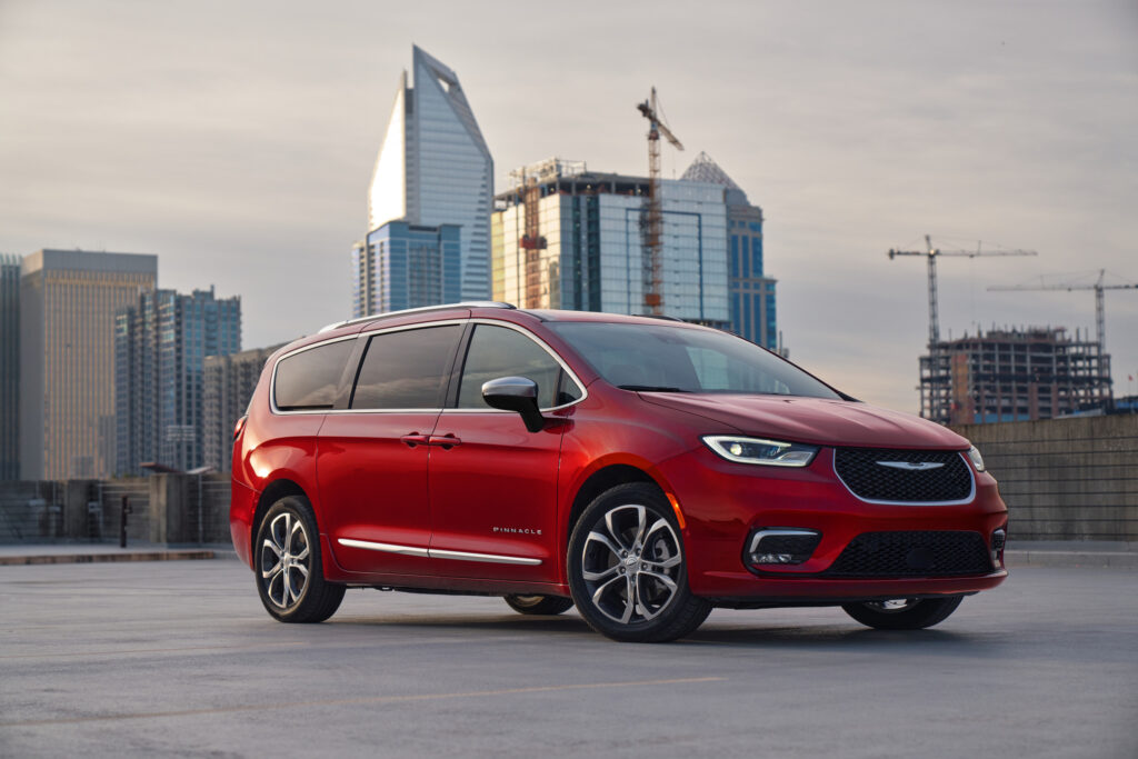 Red Chrysler Pacifica Pinnacle minivan parked on a rooftop with a city skyline, featured in our Chrysler Pacifica Review.