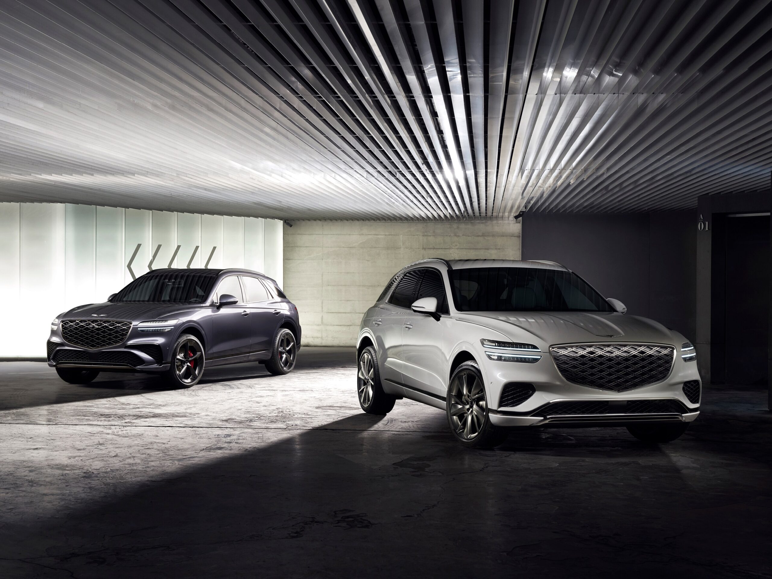 Two Genesis GV70 luxury SUVs shown in a modern indoor garage setting for a Genesis GV70 Review.