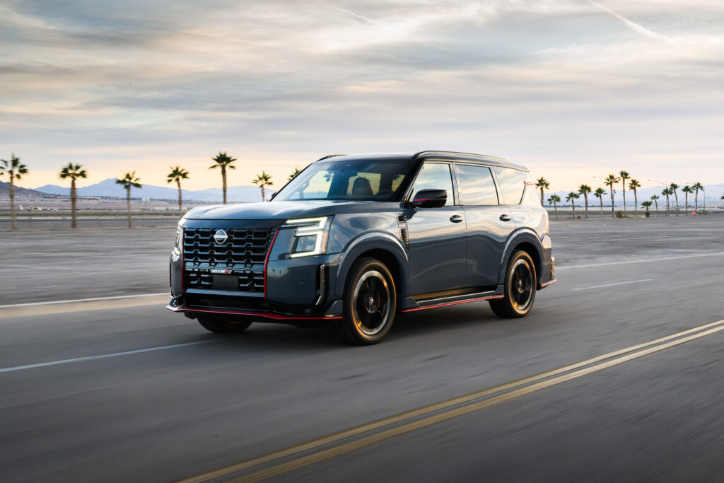 Gray Nissan Armada SUV driving on an open road with palm trees and mountains in the background for a Nissan Armada Review.