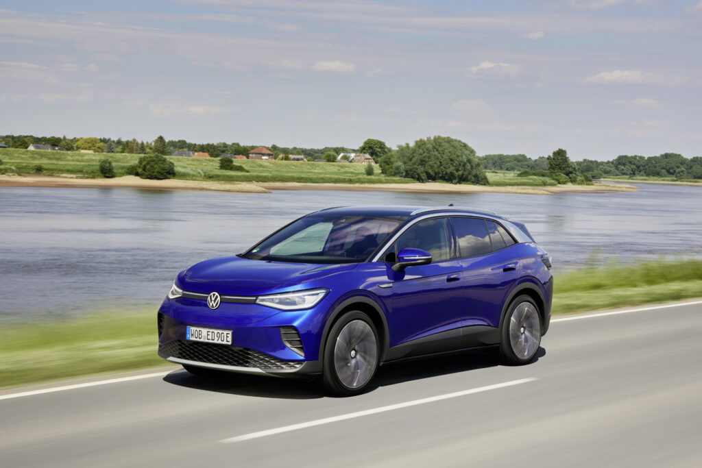 Blue Volkswagen ID.4 electric SUV driving on a road beside a river for a Volkswagen ID.4 Review.