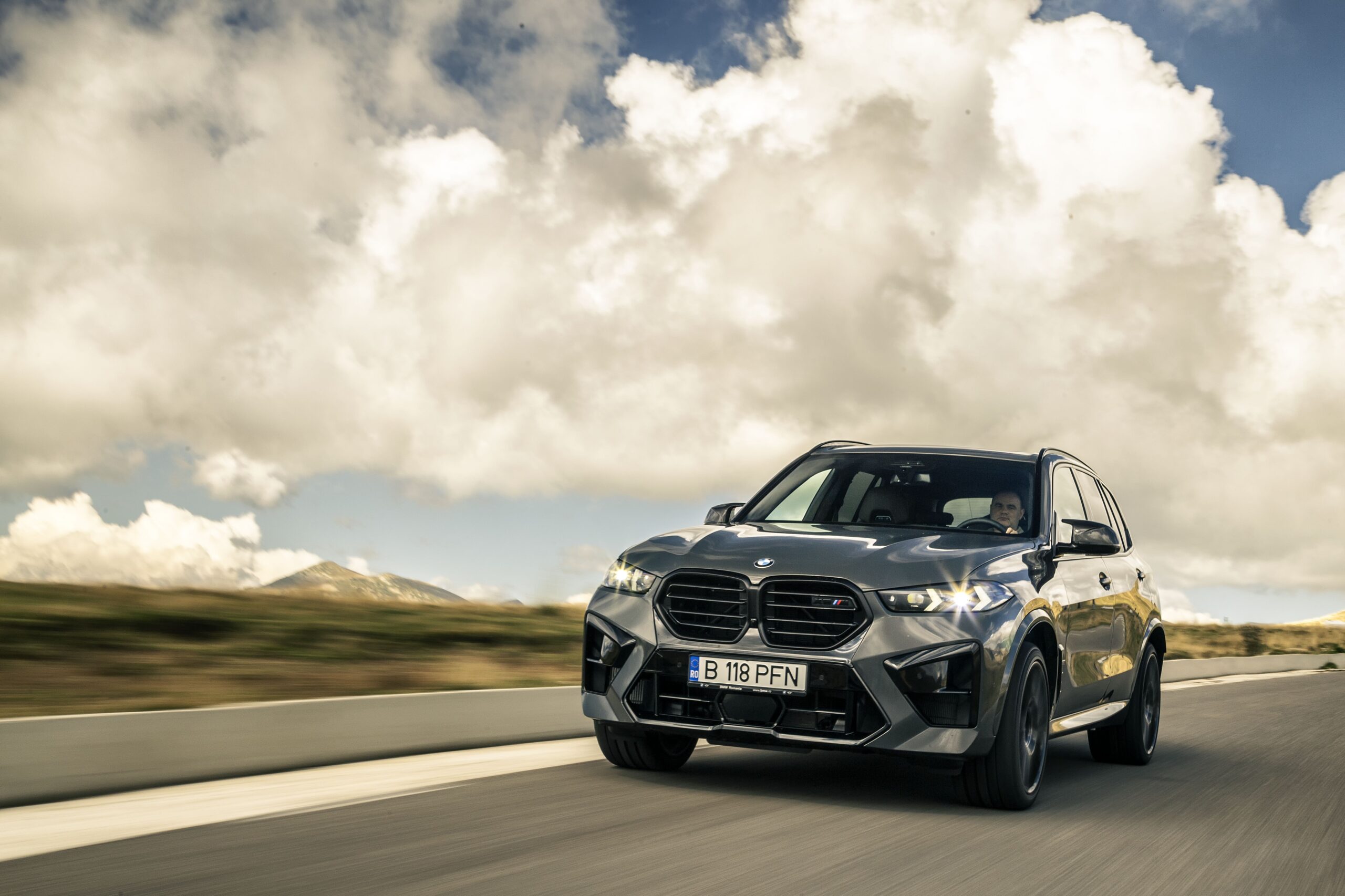 A BMW X5 driving on a desert road at sunset with lens flare, featured in our BMW X5 Review.