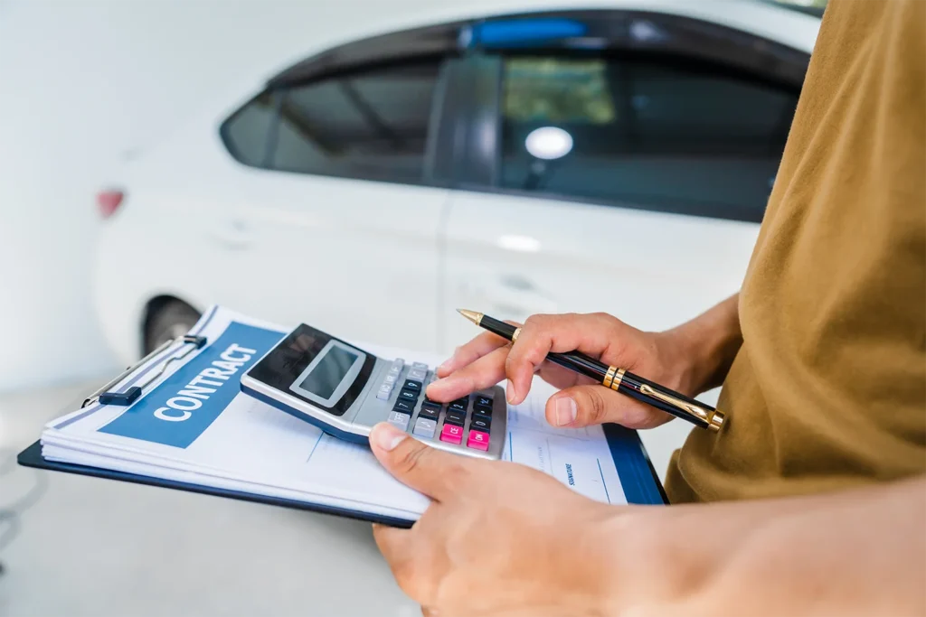 Buyer reviewing a car purchase contract and calculator during a dealership price negotiation