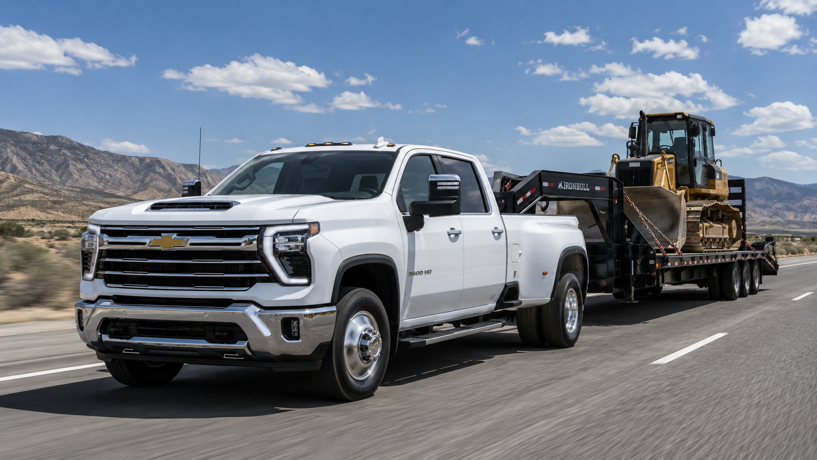 2026 Chevrolet Silverado 3500HD Crew Cab DRW in white towing a Caterpillar track loader on an IronBull gooseneck trailer on a desert highway