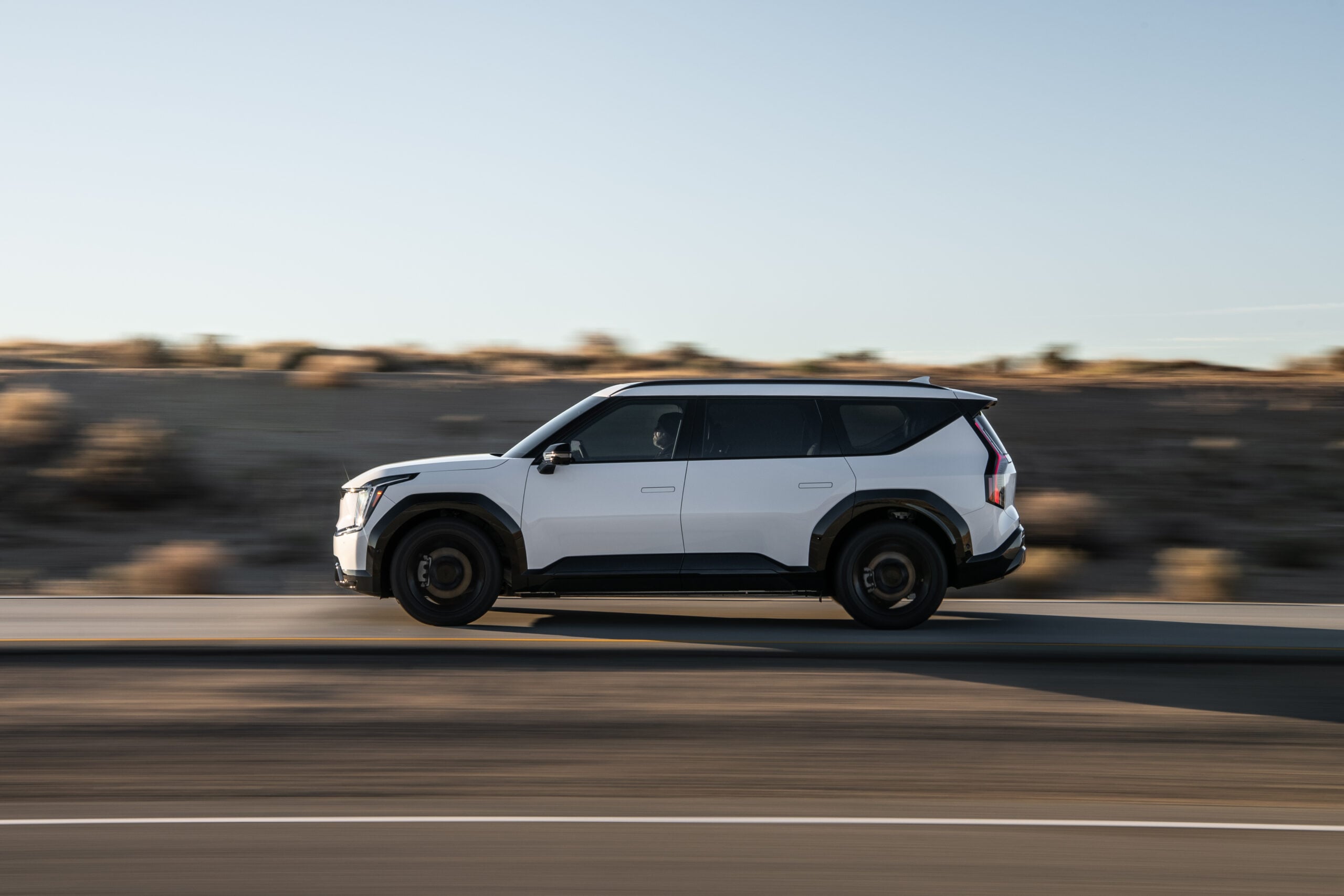 2026 Kia EV9 three-row electric SUV in white parked on a scenic road showing its bold exterior design