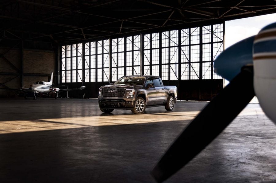Gray 2026 GMC Sierra 1500 pickup truck parked inside an airplane hangar with a private jet and propeller in the background