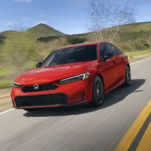 2026 Honda Civic Sedan in red driving on a scenic highway
