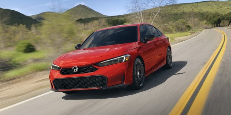 2026 Honda Civic Sedan in red driving on a scenic highway
