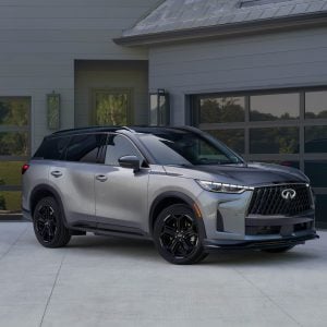 Silver Infiniti QX60 shown in a front three-quarter view outside a modern home, featured in our Infiniti QX60 Review.