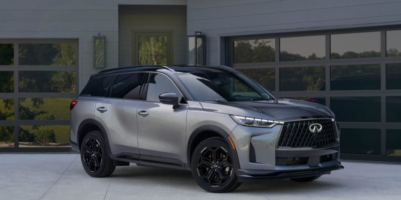 Silver Infiniti QX60 shown in a front three-quarter view outside a modern home, featured in our Infiniti QX60 Review.