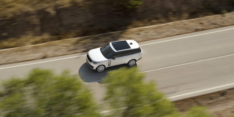 White Range Rover luxury SUV driving on a paved road in an overhead view for a Range Rover Review.