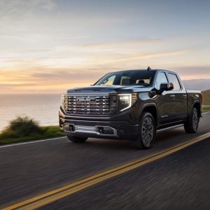 2026 GMC Sierra 1500 Denali driving on a coastal highway at sunset, featured in GMC Sierra 1500 Review
