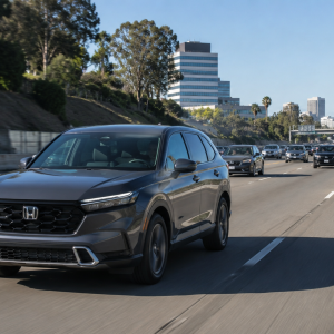 Gray Honda SUV driving in the left lane on a busy highway, with multiple cars ahead and a city skyline in the distance under a clear blue sky