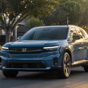 2026 Honda Prologue in North Shore Pearl driving through a quiet suburban neighborhood at golden hour with tree-lined streets and homes visible in the background