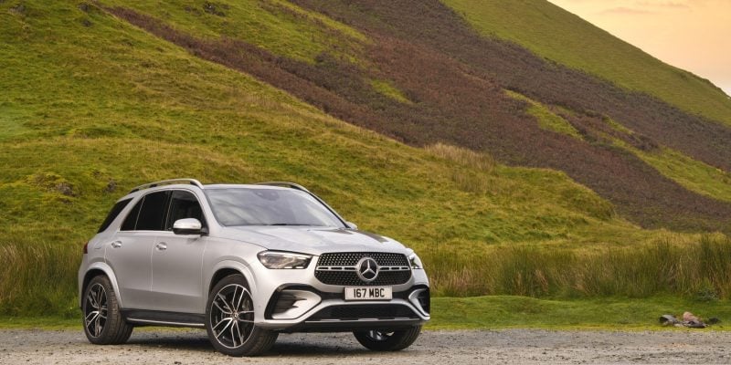 Silver Mercedes-Benz GLE luxury SUV parked in front of green hills and open countryside for a Mercedes-Benz GLE Review.