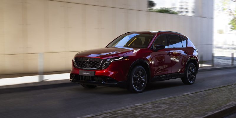 Mazda CX-5 Review image of a red 2026 Mazda CX-5 driving, front three-quarter exterior view