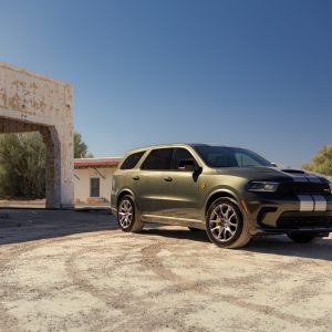 Green Dodge Durango parked in a desert-style setting near a stucco building, featured in our Dodge Durango Review.