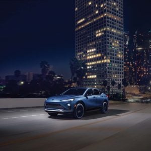 2026 Buick Envista in dark blue metallic parked on an urban street showcasing its fastback coupe silhouette and swept-back roofline