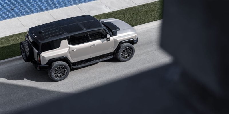 2026 GMC HUMMER EV SUV in dark finish parked on rugged terrain showcasing its bold stance and off-road presence