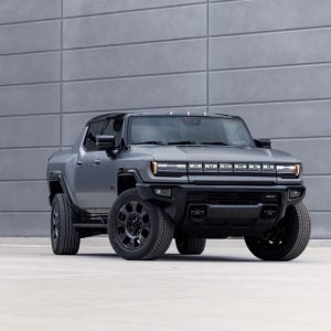 2026 GMC HUMMER EV Pickup in Moonstone Gray parked on rugged terrain with mountains in the background