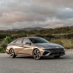 2026 Hyundai Elantra in Cyber Gray Metallic parked on a clean urban street, front three-quarter view showing the sharp angular grille and LED headlights