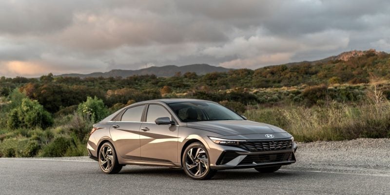 2026 Hyundai Elantra in Cyber Gray Metallic parked on a clean urban street, front three-quarter view showing the sharp angular grille and LED headlights