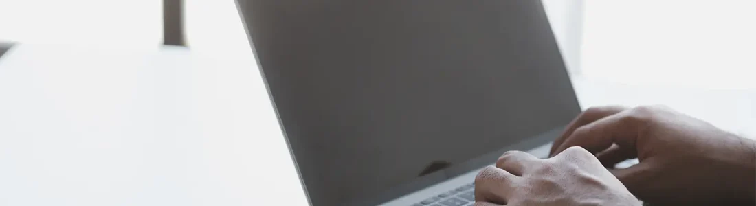 Person using a laptop to research invoice price lookup sources for accurate vehicle pricing data