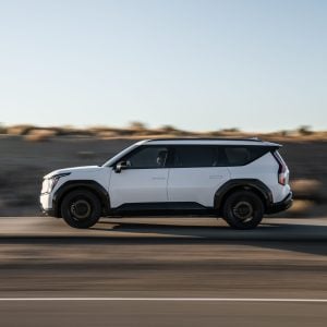 2026 Kia EV9 three-row electric SUV in white parked on a scenic road showing its bold exterior design