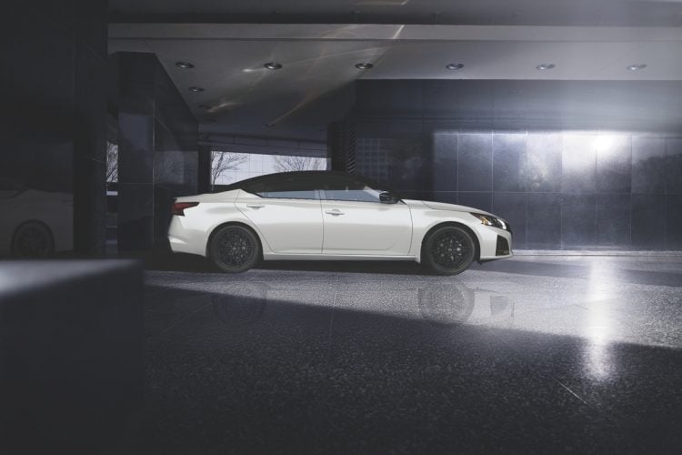 White 2026 Nissan Altima sedan shown in side profile, parked in a dark garage with dramatic overhead lighting