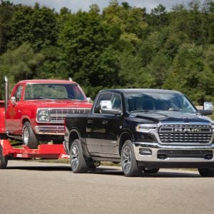 2026 Ram 1500 towing a classic red Dodge pickup on a trailer, featured in Ram 1500 Review
