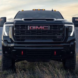 2025 GMC Sierra HD AT4X in Onyx Black facing forward on a hilltop with mountain range and dramatic sky in the background