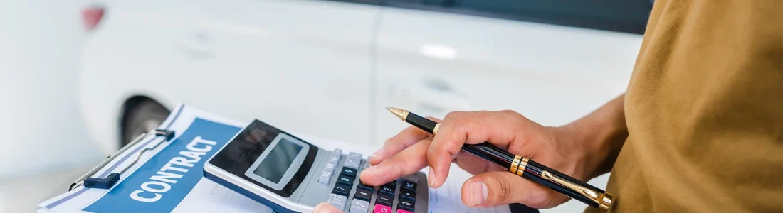 Buyer reviewing a car purchase contract and calculator during a dealership price negotiation