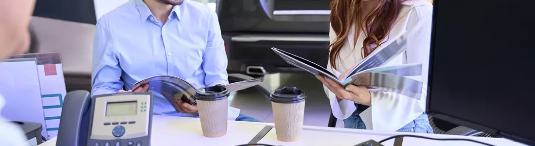 Couple reviewing vehicle pricing information with a salesperson at a car dealership