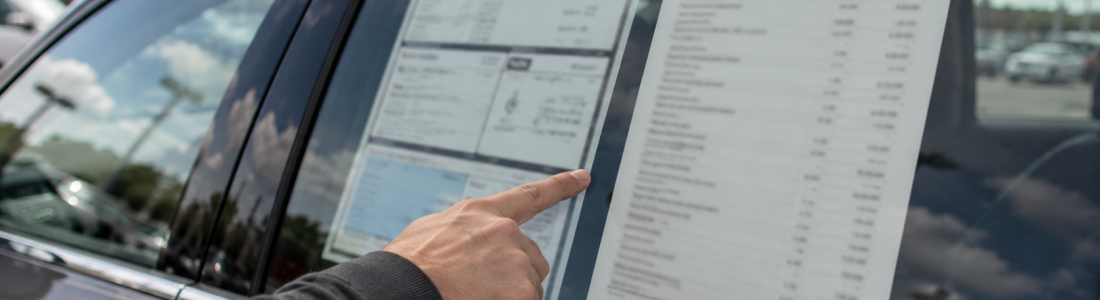 Monroney sticker vs. dealer addendum comparison on a new car window