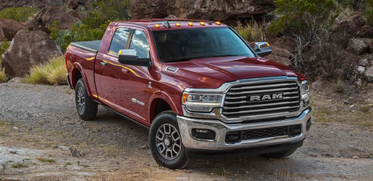 A Built Ram Off-Roader crawls over a trailer to get a broken semi-truck